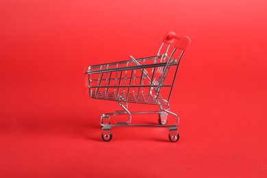 Photo of Small metal shopping cart on red background