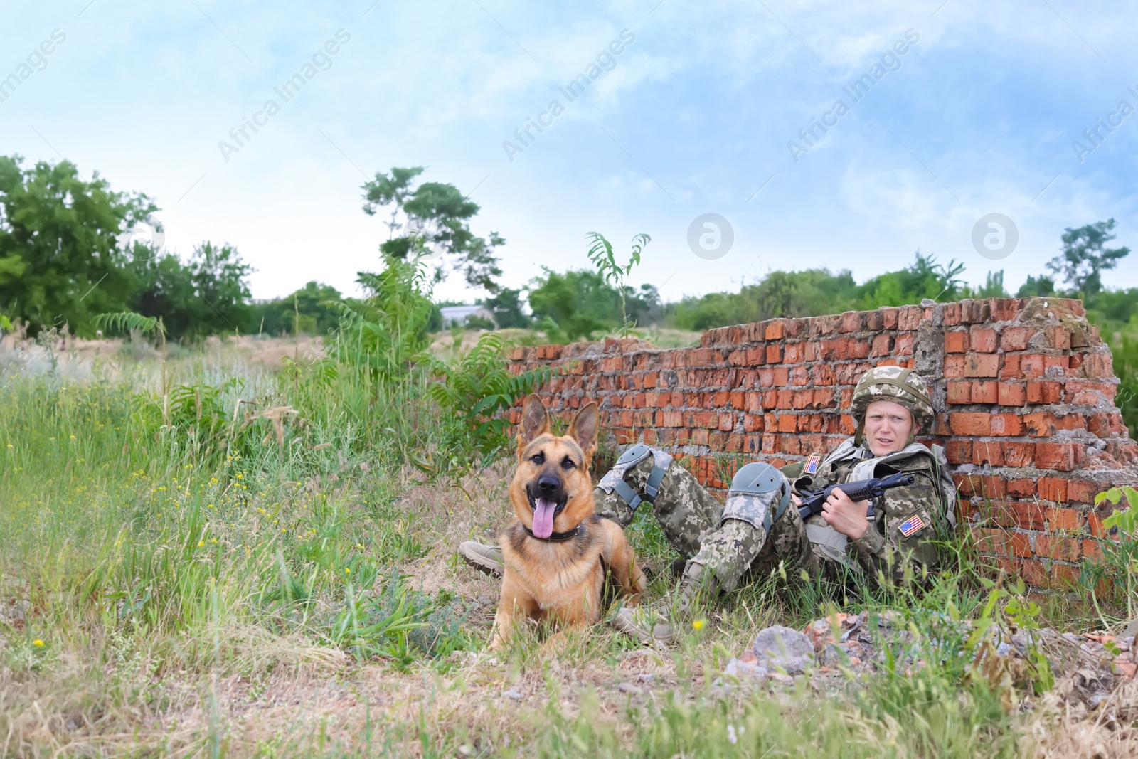 Photo of Man in military uniform with German shepherd dog near broken brick wall