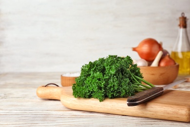 Wooden board with fresh curly parsley on table