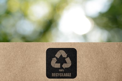 Image of Paper bag with recycling symbol on blurred green background. Eco friendly package