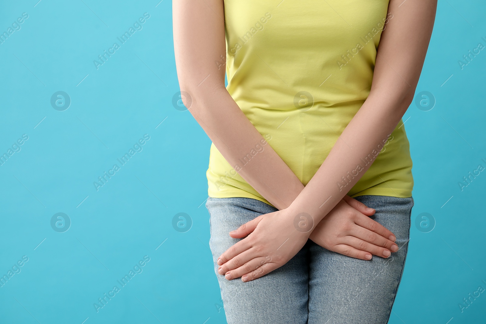 Photo of Woman suffering from cystitis on light blue background, closeup. Space for text