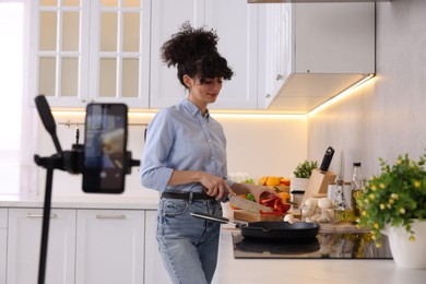 Photo of Food blogger cooking while recording video in kitchen