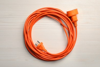Photo of Extension cord on white wooden floor, top view. Electrician's equipment
