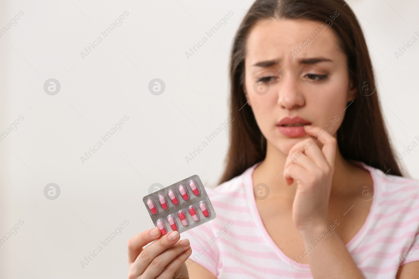 Photo of Young woman with pills on light background, space for text