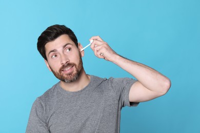 Man using ear spray on light blue background