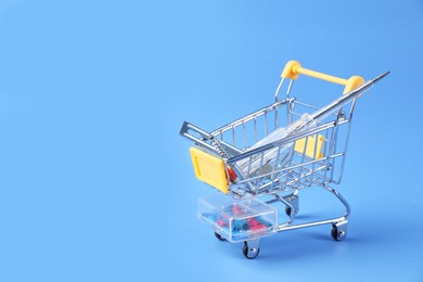 Photo of Small shopping cart with set of construction tools on light blue background. Space for text