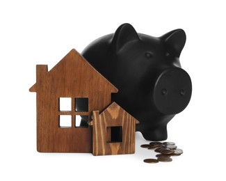 Piggy bank, wooden house models and coins on white background. Saving money concept