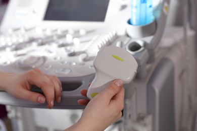 Sonographer holding ultrasound machine probe in clinic, closeup