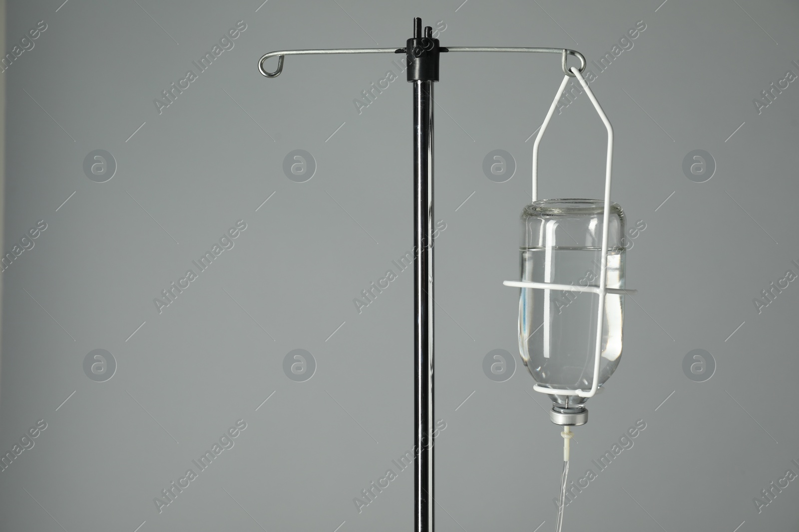 Photo of IV infusion set on pole against grey background. Space for text