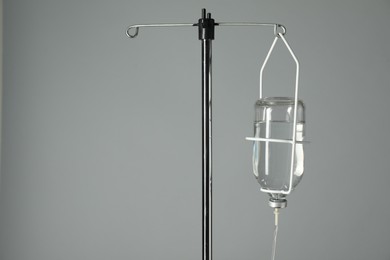 IV infusion set on pole against grey background. Space for text