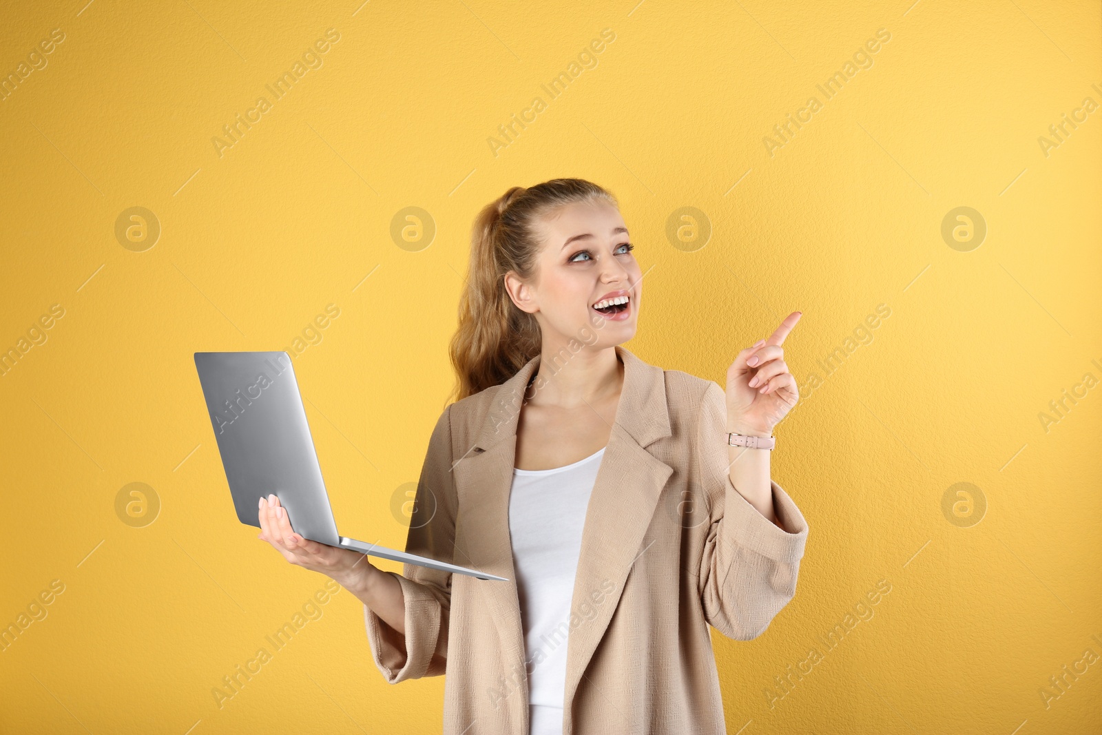 Photo of Portrait of beautiful young woman with laptop on yellow background