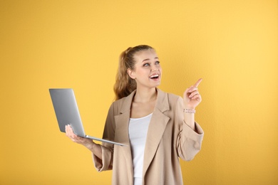 Photo of Portrait of beautiful young woman with laptop on yellow background