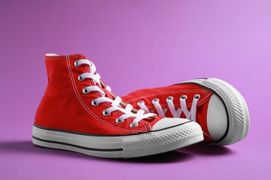 Photo of Pair of new stylish red sneakers on purple background