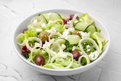 Bowl of tasty salad with leek, olives and cheese on white textured table, closeup