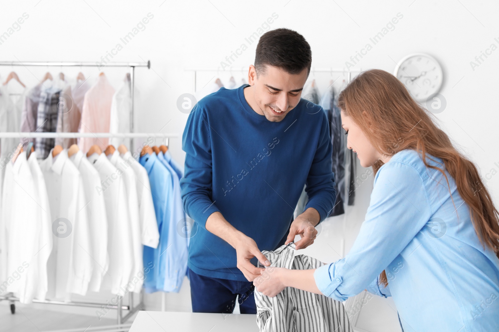 Photo of Young woman giving shirt to dry-cleaner's worker