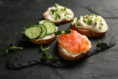 Delicious sandwiches with cream cheese and other ingredients on black table