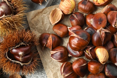 Photo of Delicious roasted edible chestnuts on grey table, flat lay