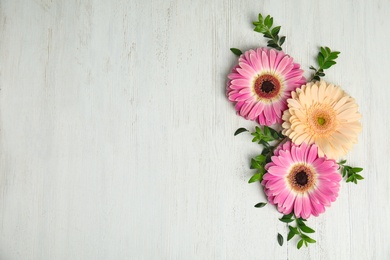 Photo of Flat lay composition with beautiful bright gerbera flowers on wooden background. Space for text