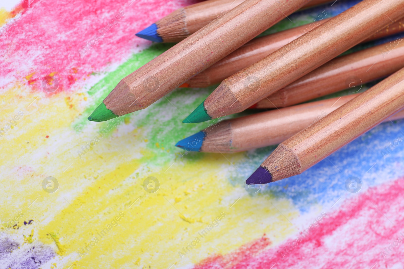 Photo of Colorful pastel pencils on abstract drawing, closeup