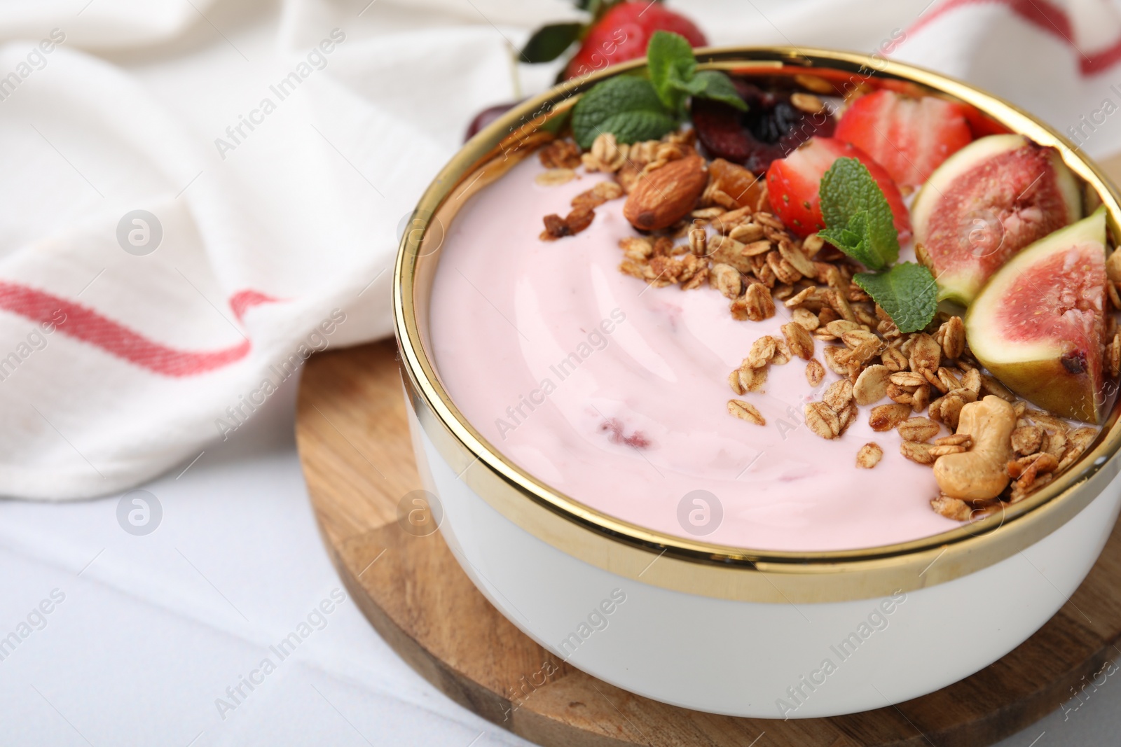 Photo of Bowl with yogurt, fruits and granola on white tiled table, closeup. Space for text