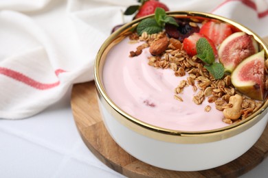 Photo of Bowl with yogurt, fruits and granola on white tiled table, closeup. Space for text