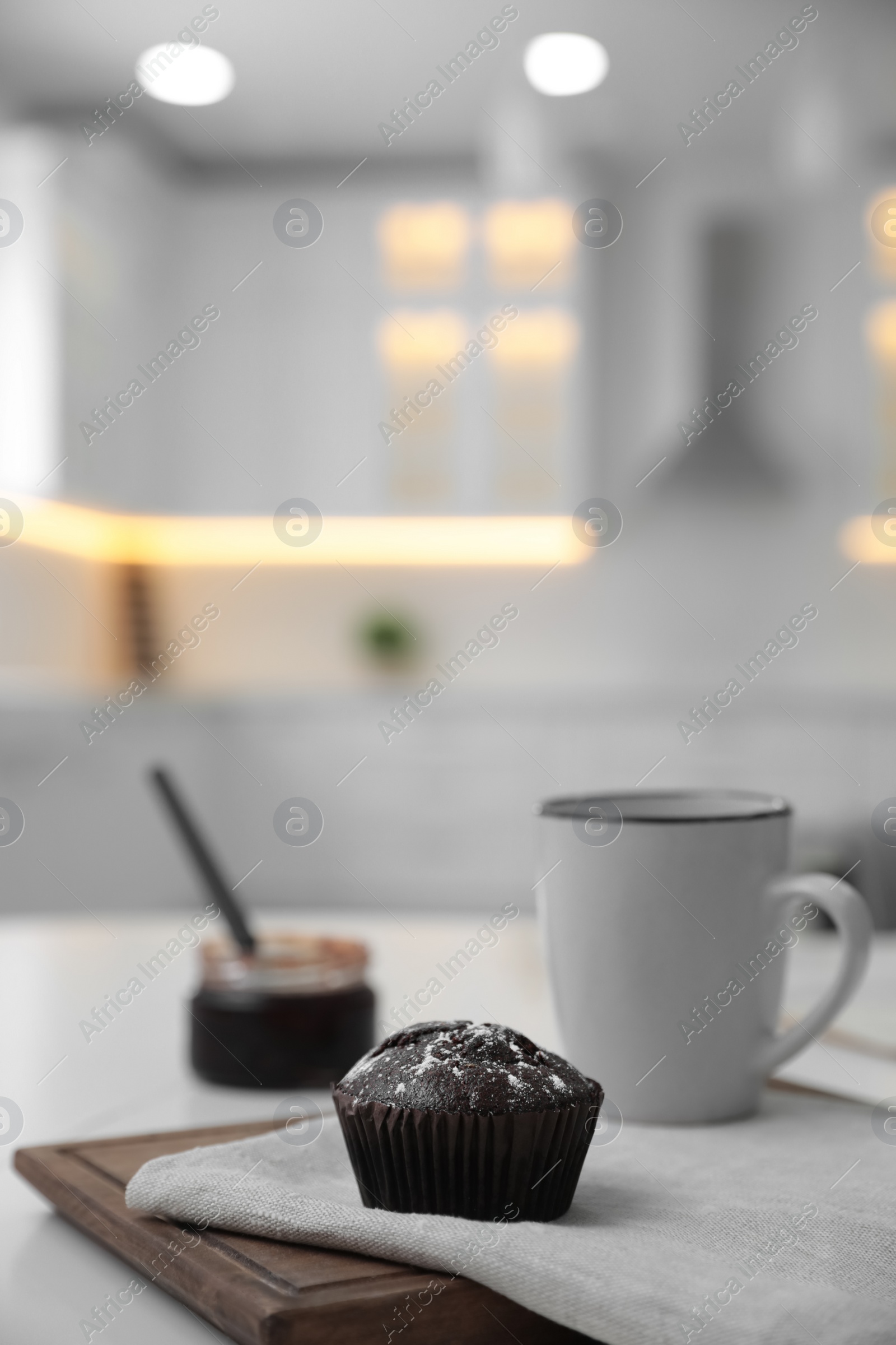 Photo of Delicious chocolate muffin on white table in kitchen. Space for text