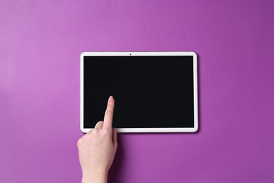 Photo of Online store. Woman using tablet on purple background, top view