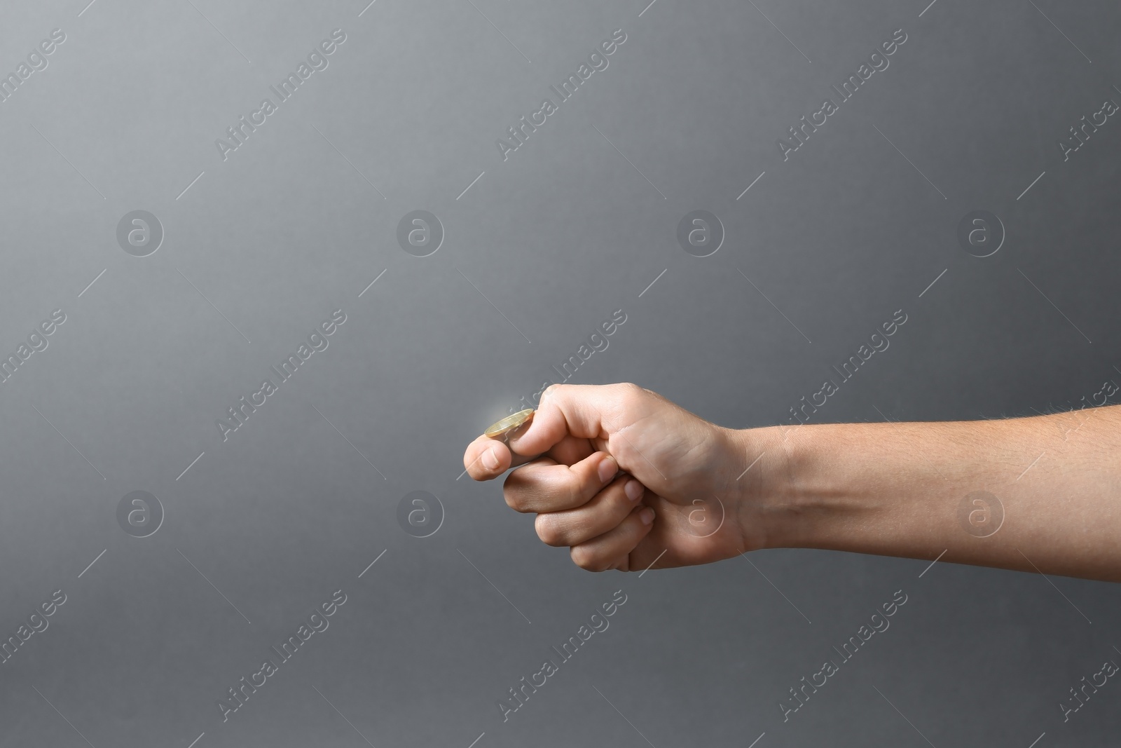 Photo of Young woman throwing coin on grey background, closeup