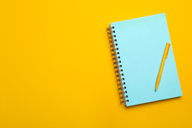 Photo of Light blue notebook and pen on yellow background, top view. Space for text