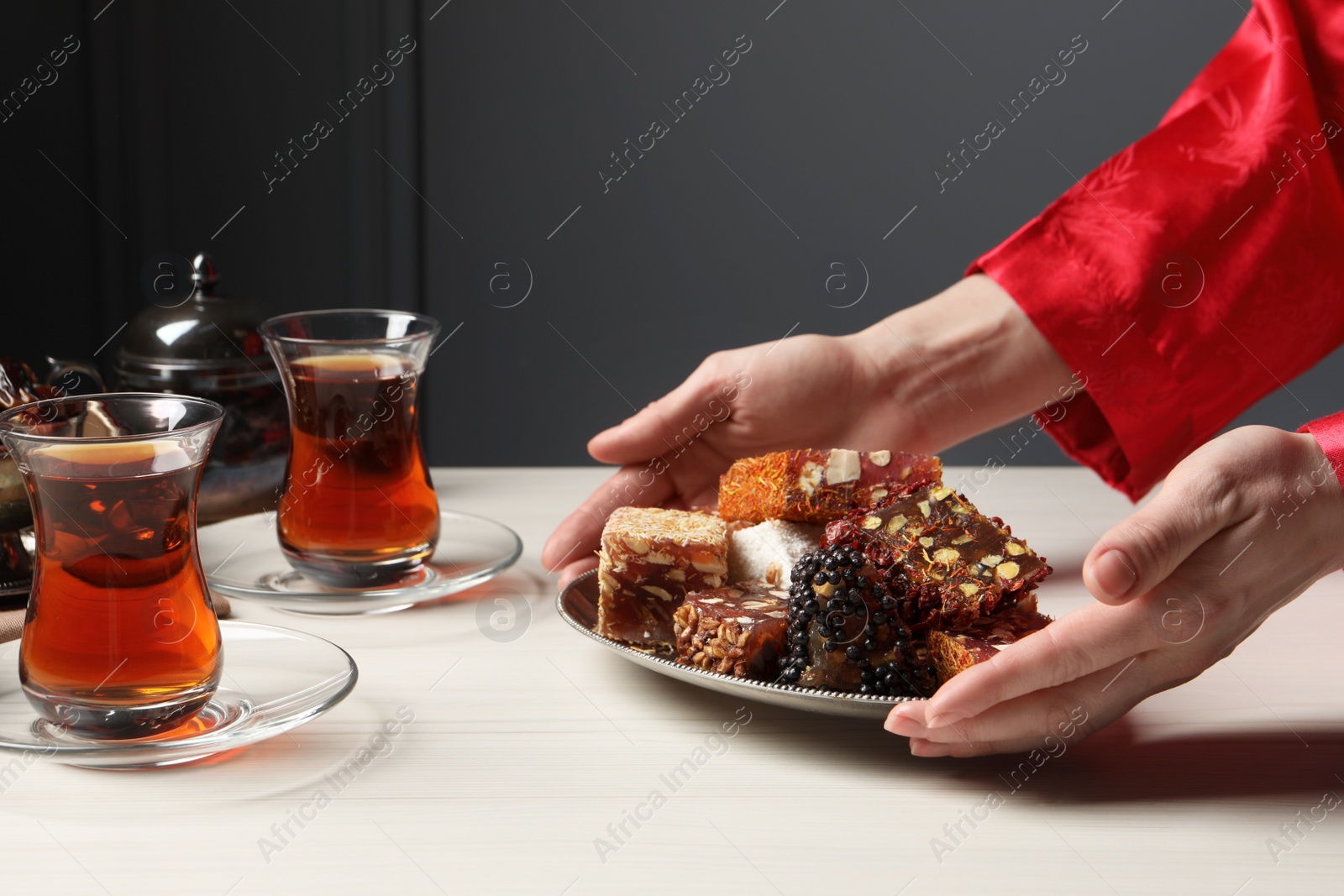 Photo of Woman serving Turkish delight on vintage tray, closeup