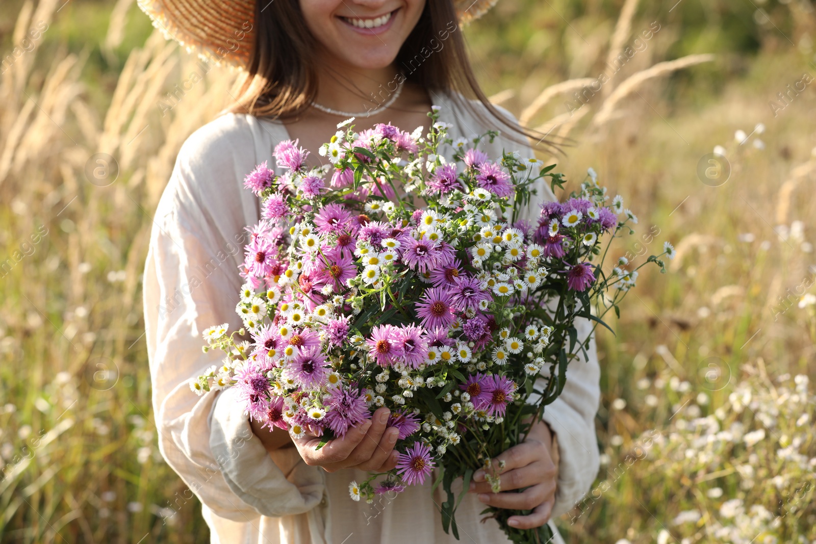 Photo of Woman holding bouquet of beautiful wild flowers outdoors, closeup