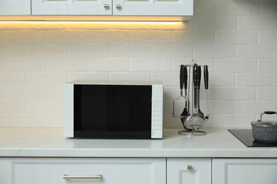 Photo of Modern microwave oven on countertop in kitchen