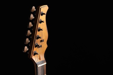 Photo of Head of electric guitar in darkness, closeup. Space for text