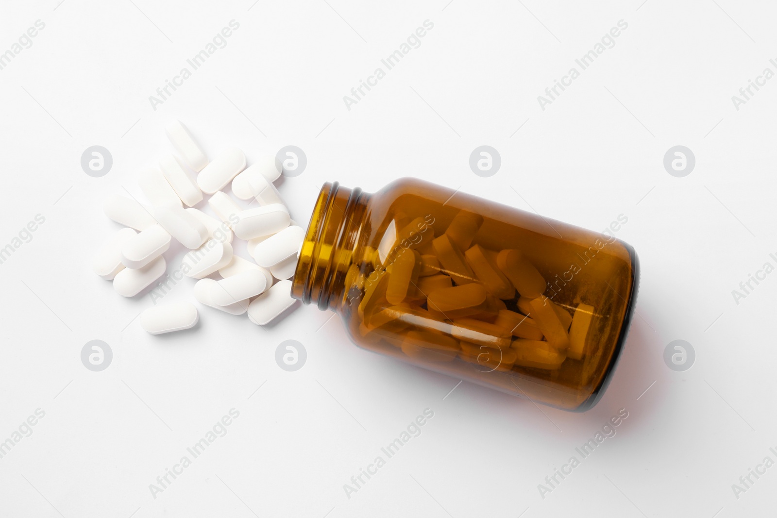 Photo of Vitamin pills and bottle on white background, top view