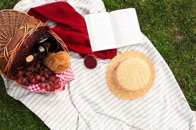 Photo of Flat lay composition with wicker basket and picnic blanket on green grass