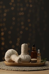 Photo of Spa composition. Herbal sacks, cosmetic products and stones on table indoors. Space for text