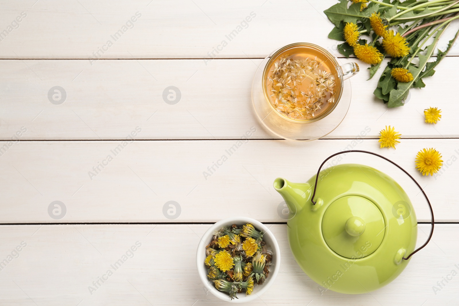 Photo of Delicious fresh tea and dandelion flowers on white wooden table, flat lay. Space for text