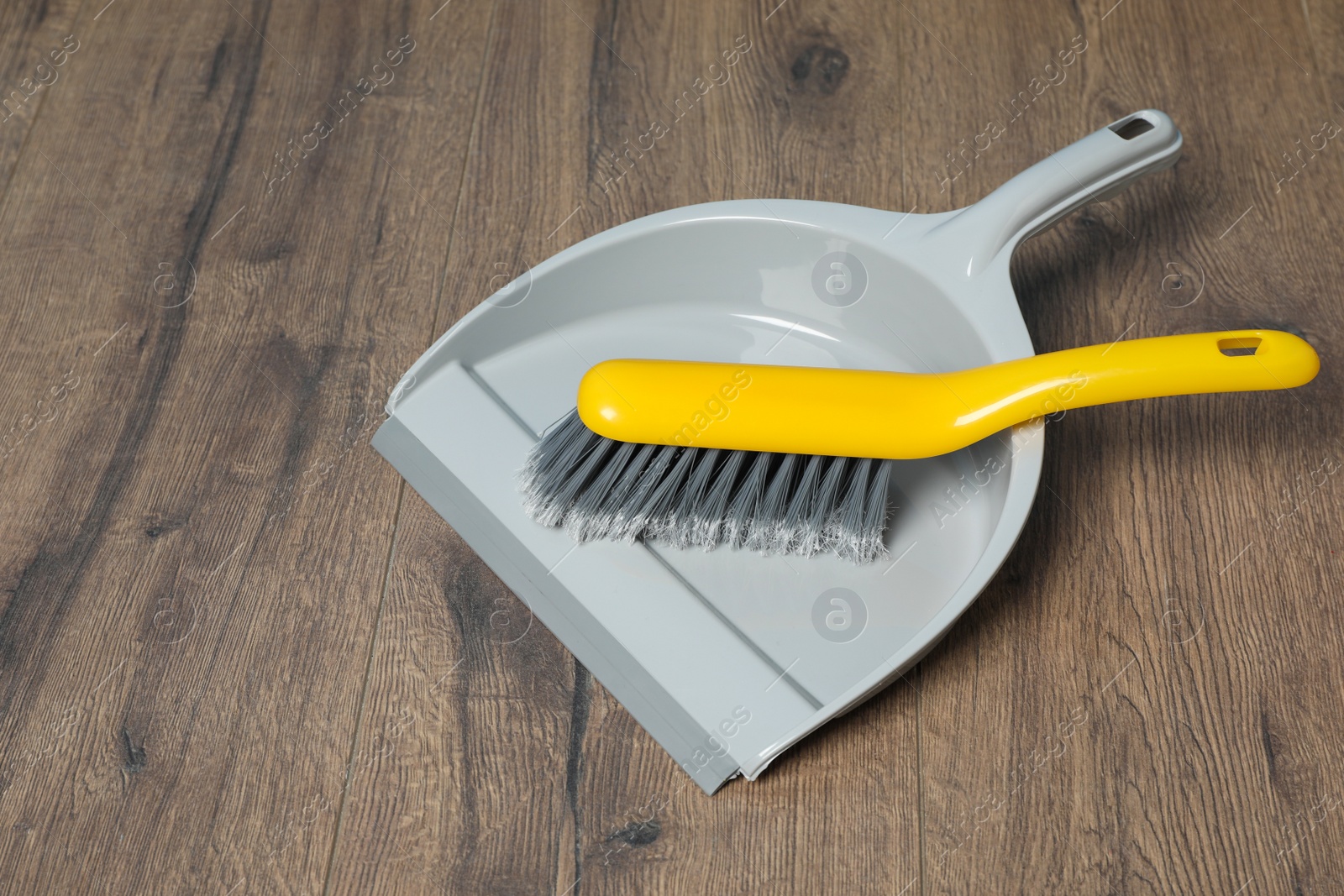 Photo of Plastic whisk broom with dustpan on wooden floor