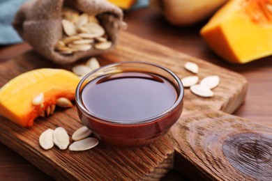 Photo of Glass bowl of pumpkin seed oil on wooden table