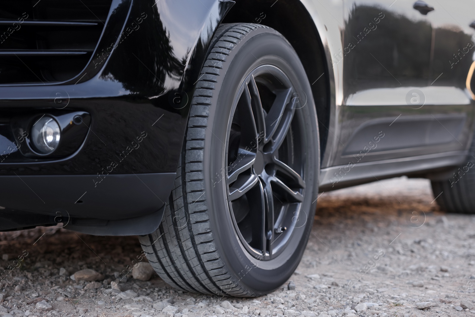 Photo of Modern black car parked on rubble road outdoors, closeup