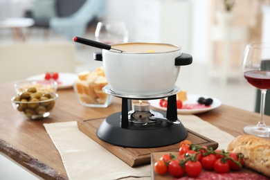 Photo of Fondue pot and different products on table indoors