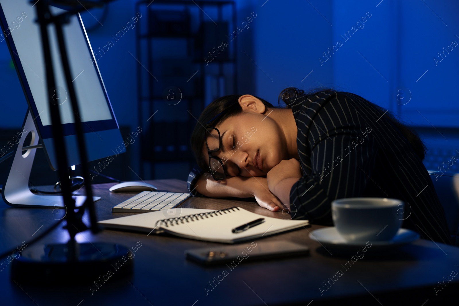 Photo of Tired overworked businesswoman napping at night in office