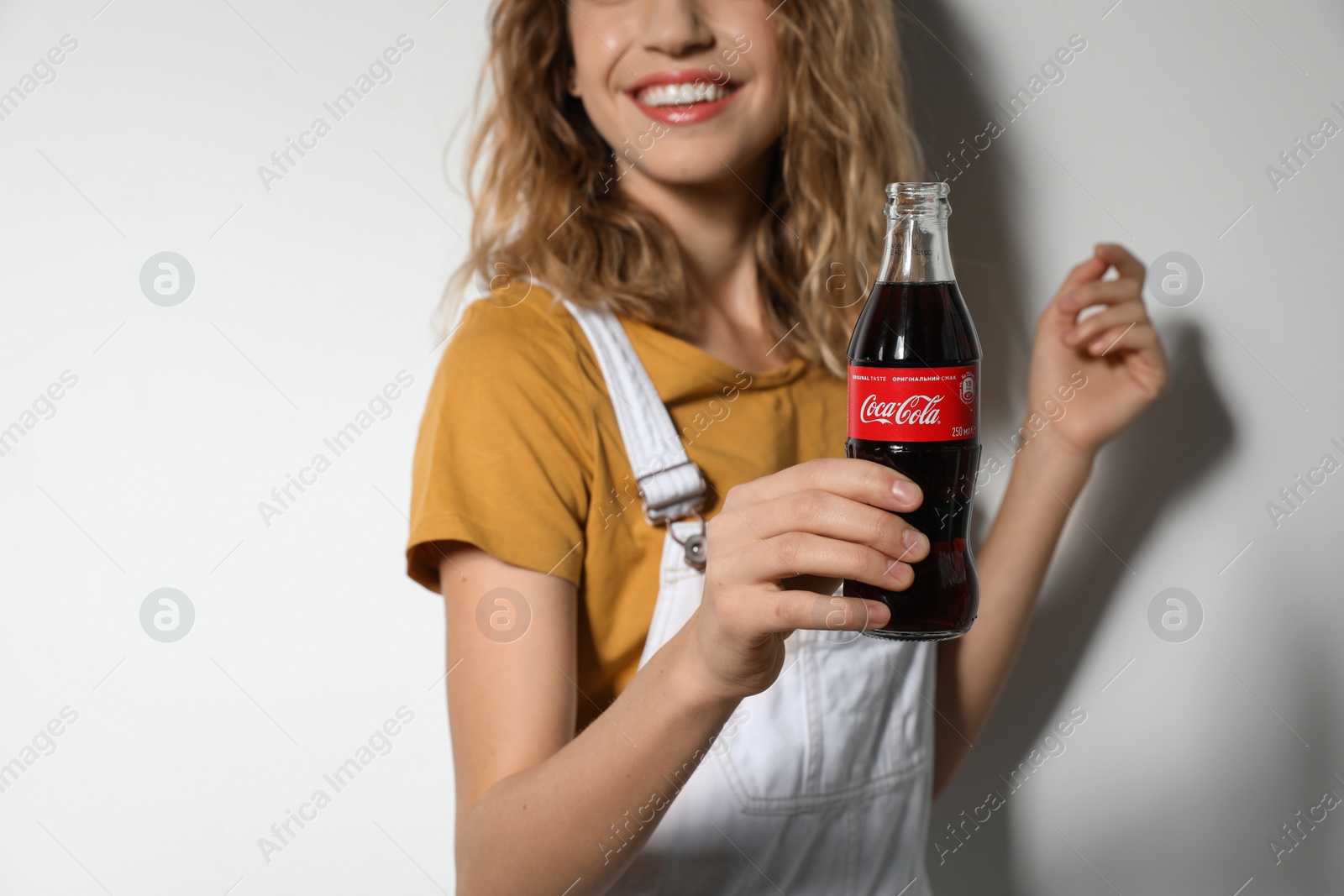 Photo of MYKOLAIV, UKRAINE - NOVEMBER 28, 2018: Young woman with bottle of Coca-Cola on white background, closeup