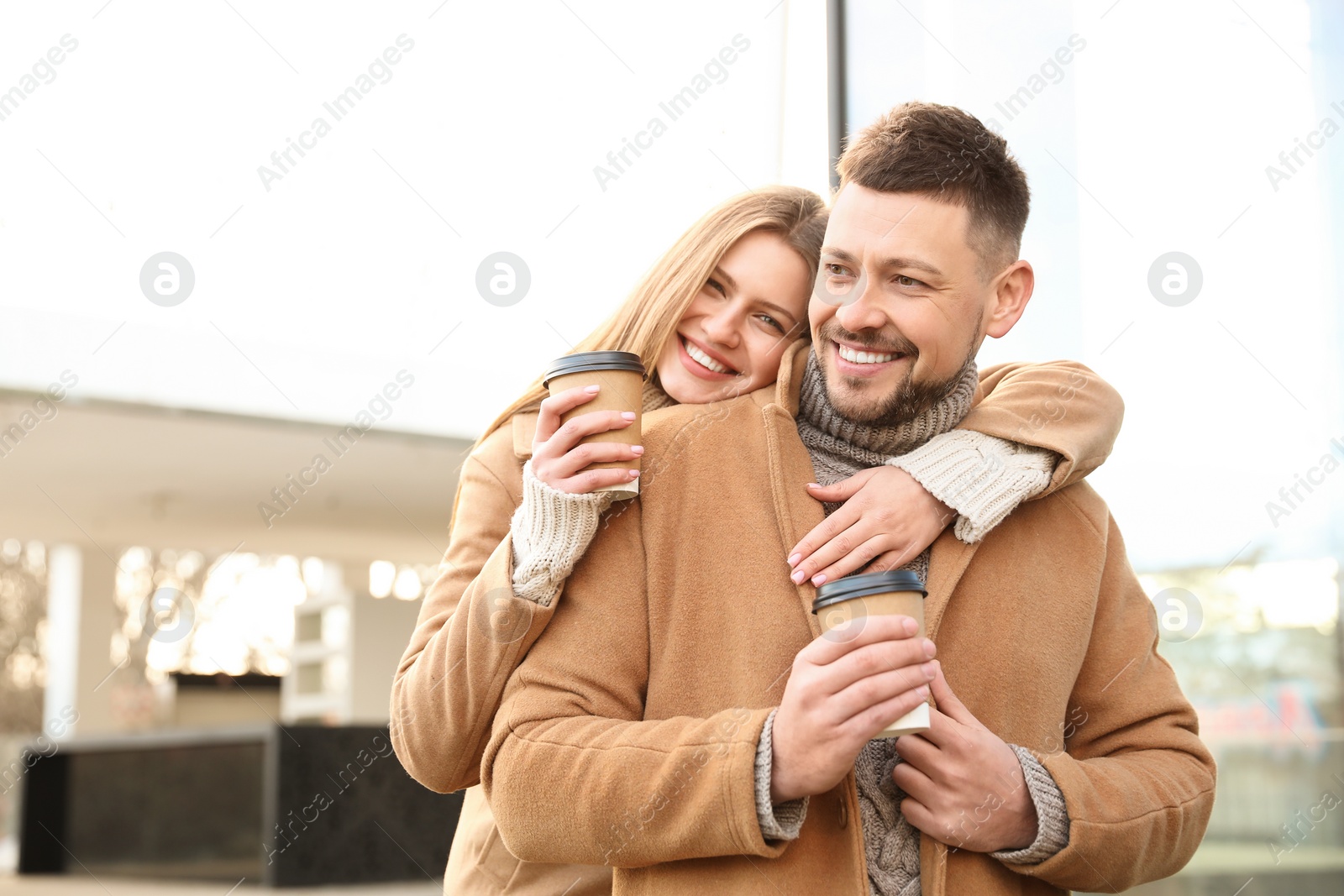 Photo of Lovely couple with cups of coffee on city street in morning