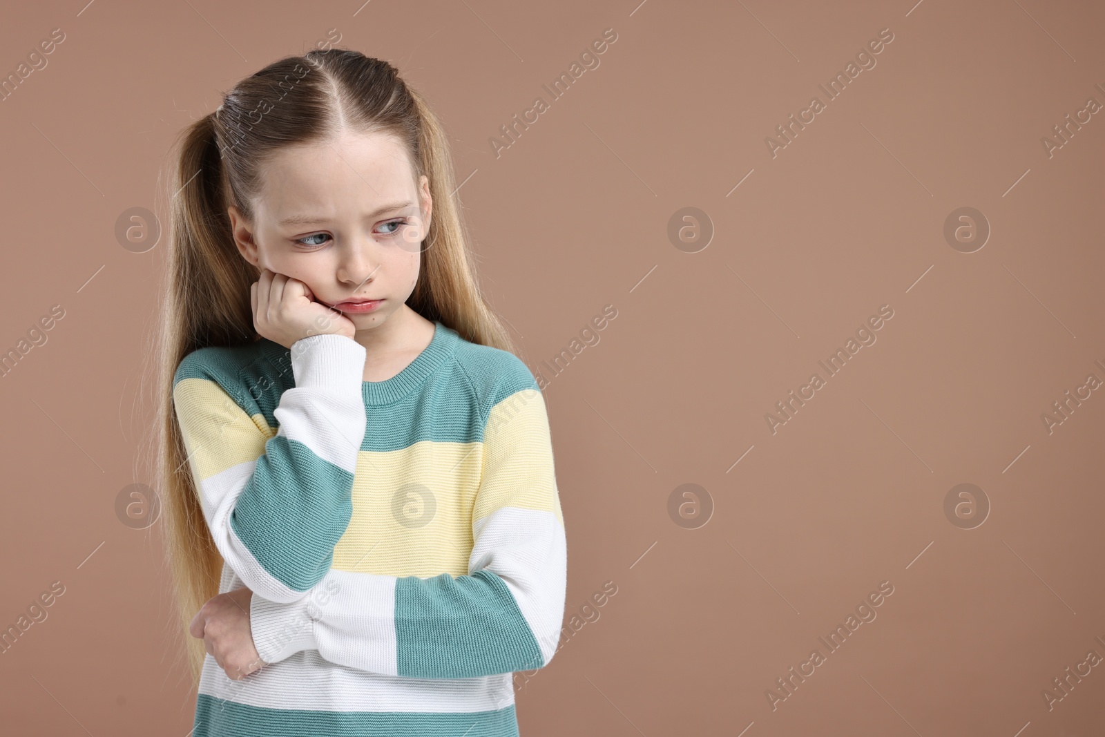 Photo of Portrait of sad girl on light brown background, space for text