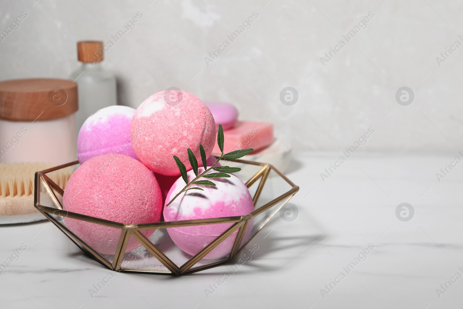 Photo of Beautiful aromatic bath bombs and green twig on white marble table, space for text