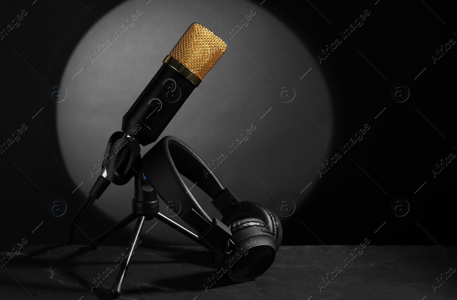 Photo of Stand with microphone and headphones on grey textured table, space for text. Sound recording and reinforcement