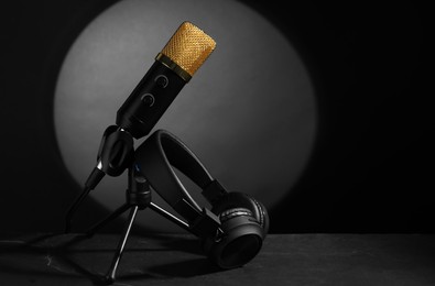 Photo of Stand with microphone and headphones on grey textured table, space for text. Sound recording and reinforcement