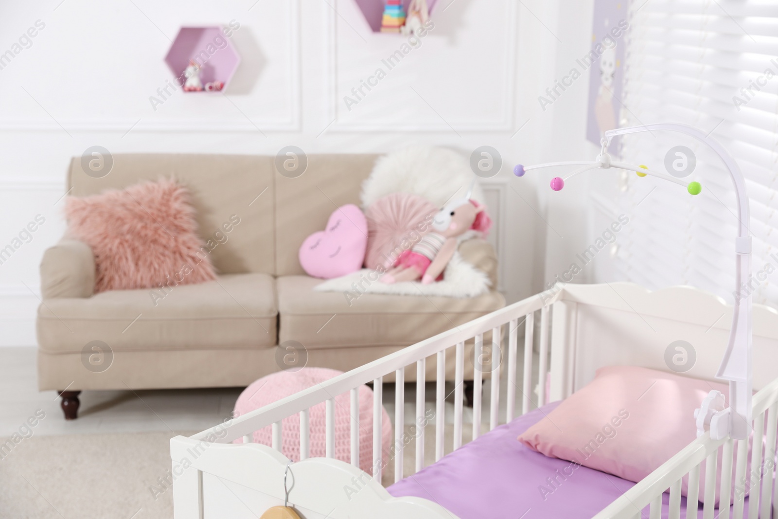 Photo of Cozy baby room with crib and sofa. Interior design