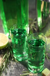 Absinthe in shot glasses on gray table, closeup. Alcoholic drink